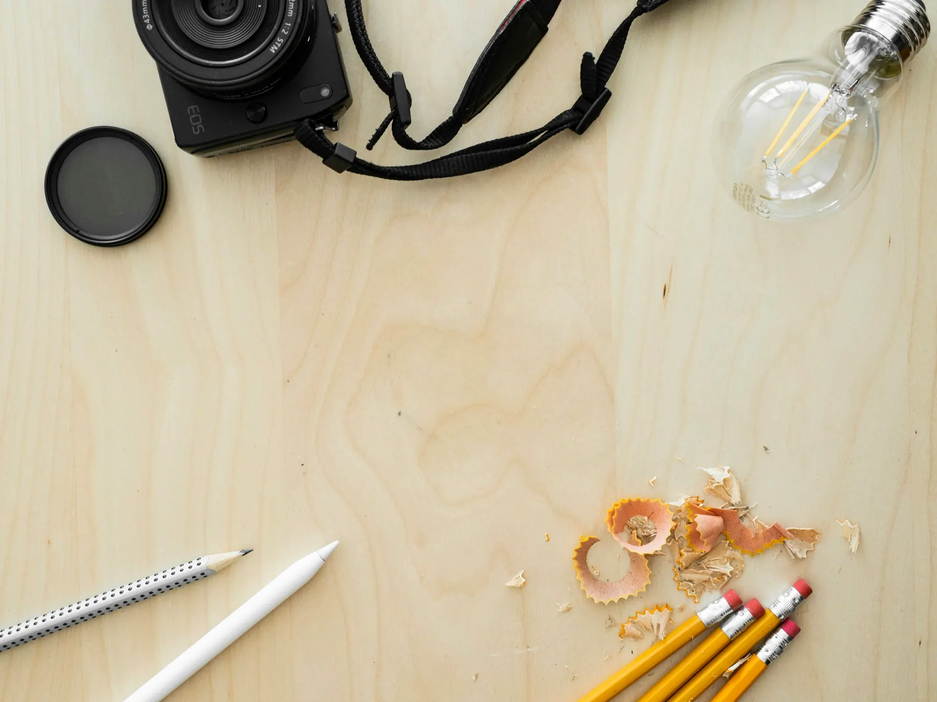 Photography equipment laid out on a surface including a camera body, lenses and memory cards.
