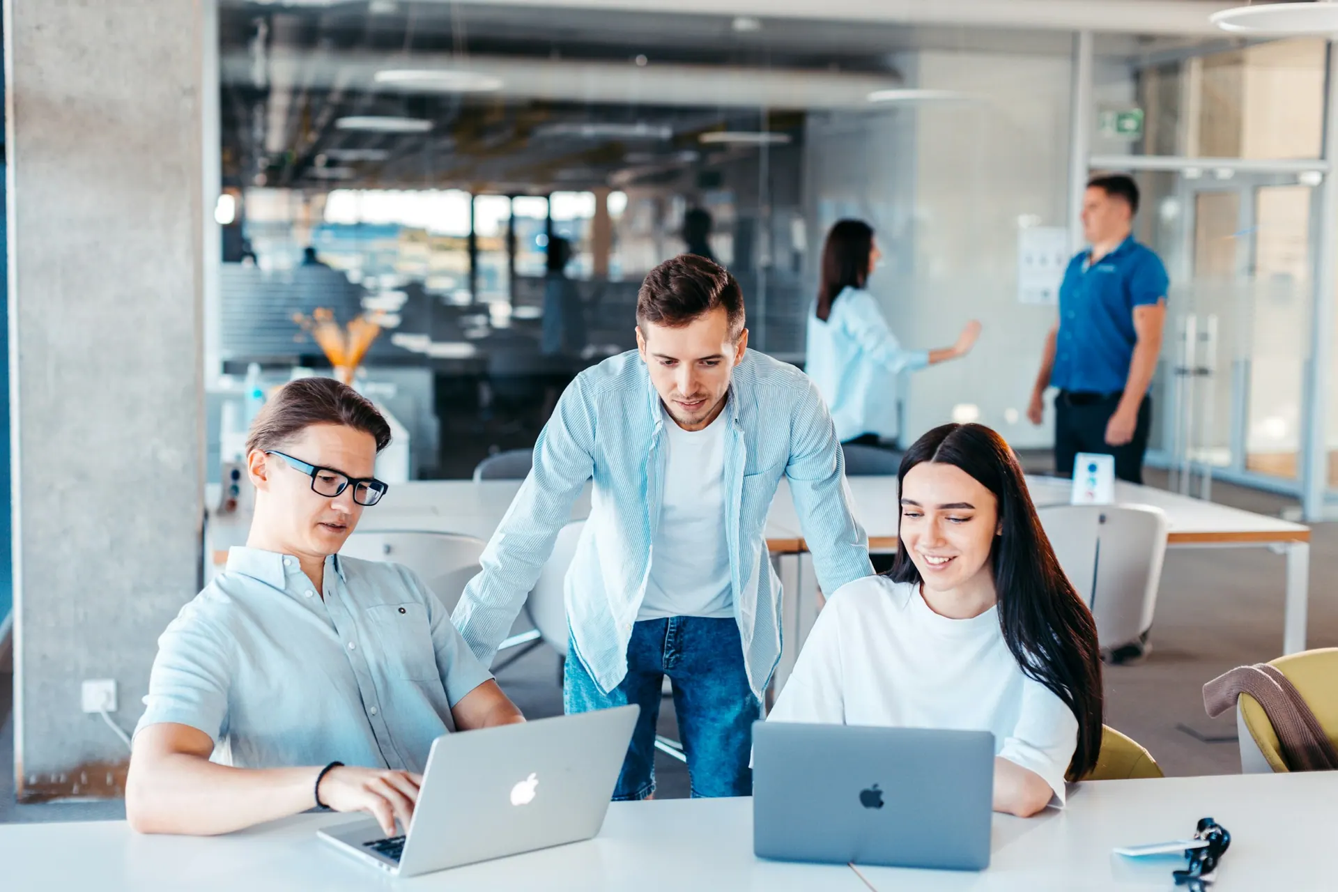 Colleagues working together around a table in a bright open-plan office.