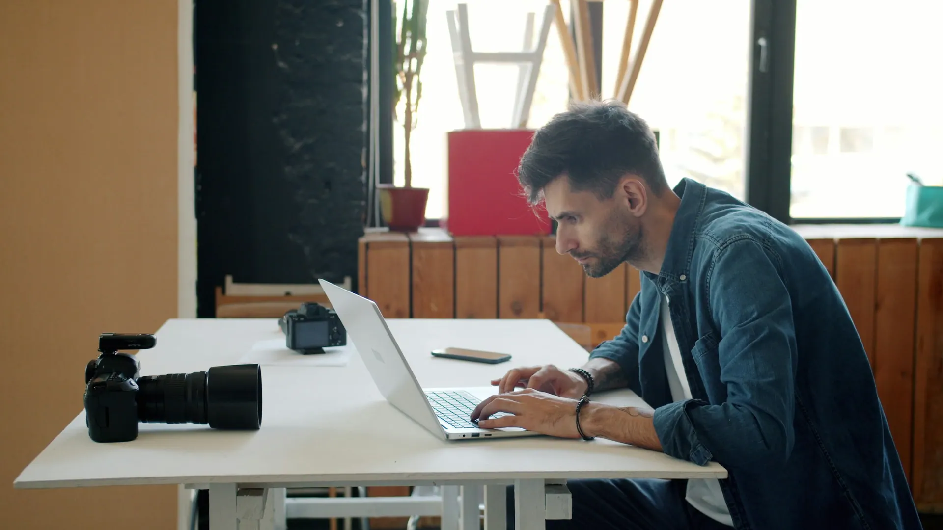 A creative production workspace with screens, notes and camera equipment arranged on a desk.