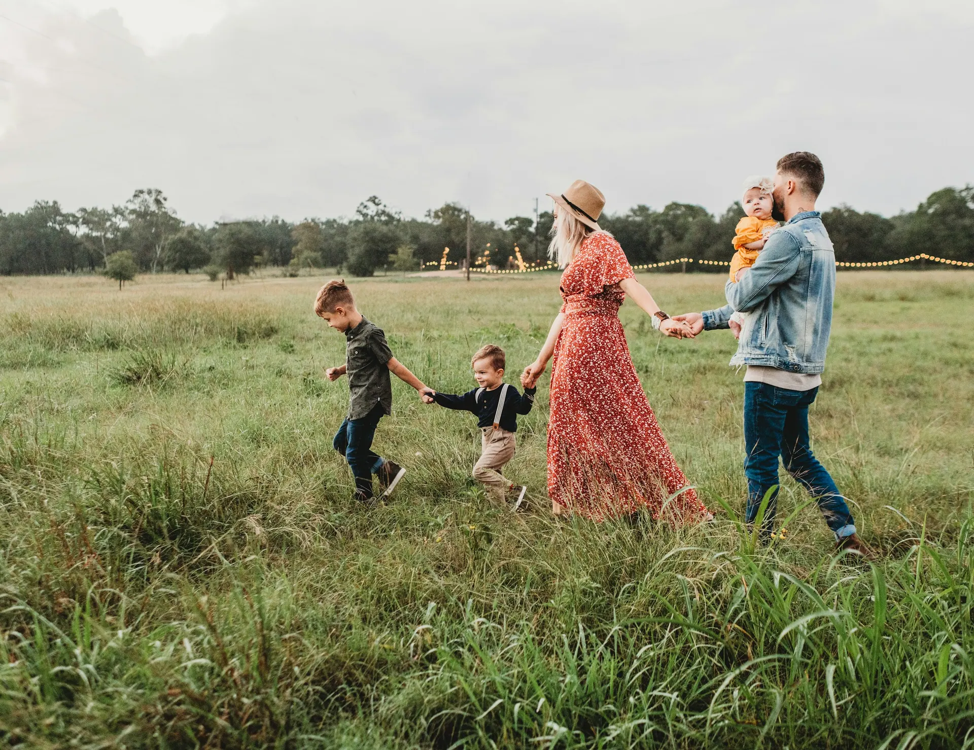 A family walking together outdoors in soft daylight, photographed from a distance.