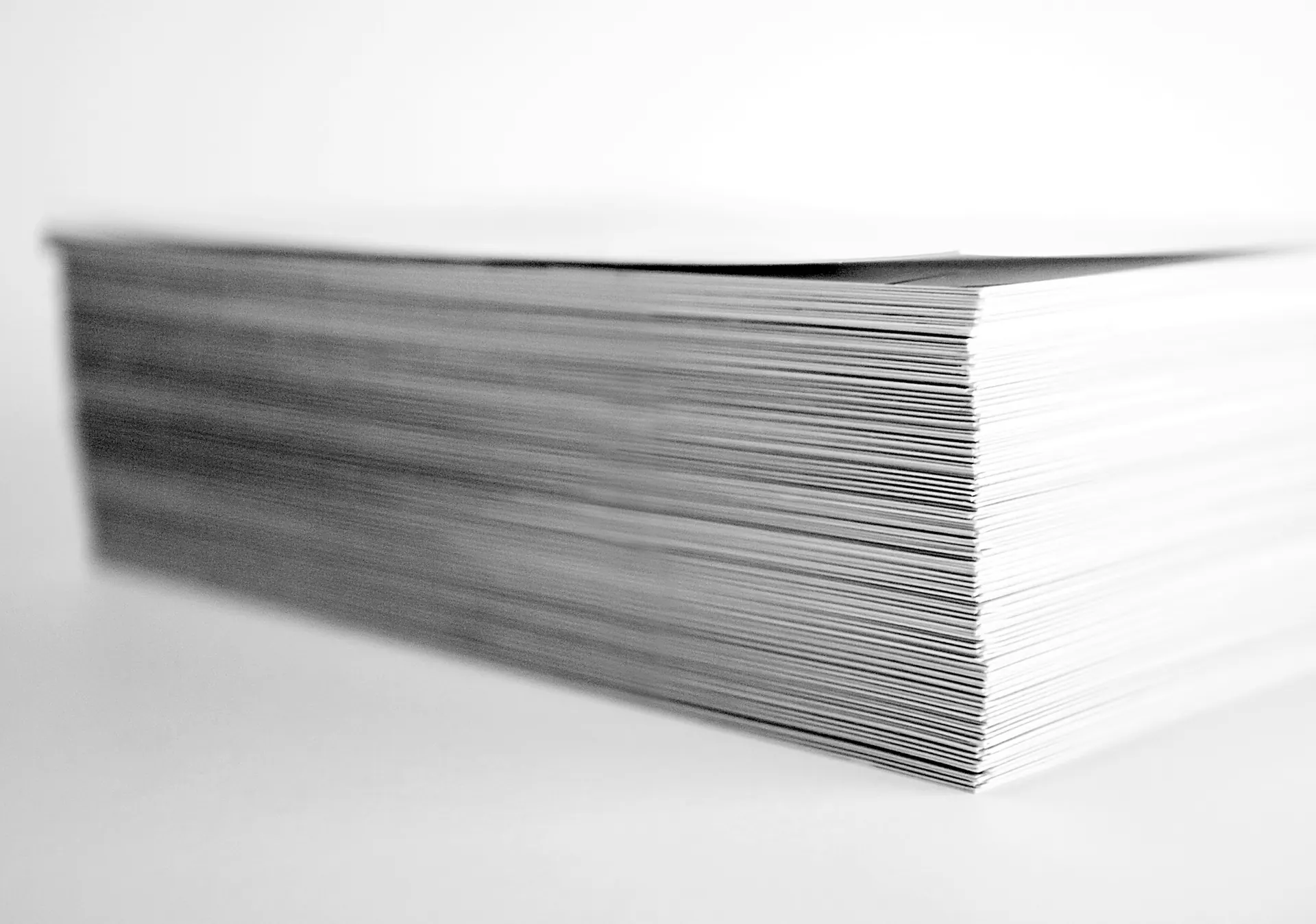 A stack of printed photographs being sorted on a clean work surface.