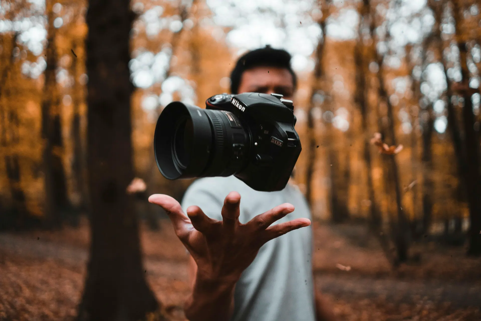 A photographer holding a professional camera while composing a shot in available light.