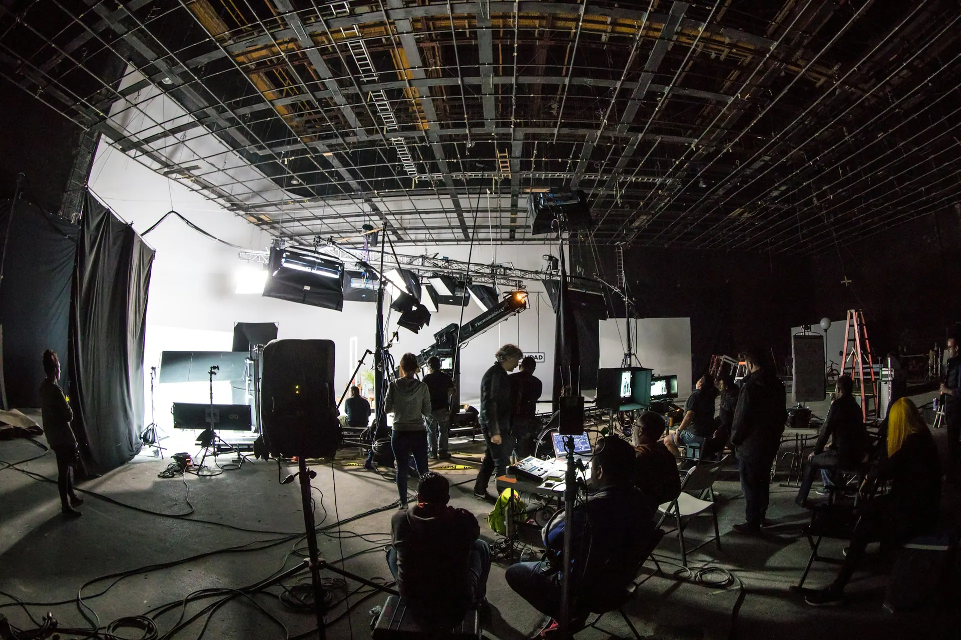 A video production set with lighting rigs and equipment positioned around a filming area.